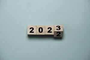 voltear de 2022 a 2023 en un cubo de bloques de madera para preparar el cambio de año nuevo y comenzar un nuevo concepto de estrategia de objetivo comercial. foto