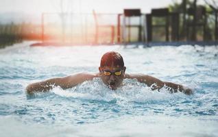 Nadador deportivo con gorra respirando realizando el estilo mariposa. nadador nadando en la piscina. concepto de natación deportiva. foto