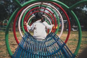 Cute asian girl play on school or kindergarten yard or playground. Healthy summer activity for children. Little asian girl climbing outdoors at playground. Child playing on outdoor playground. photo