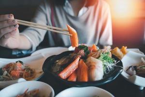 Asian woman eating a sashimi salmon. Woman using chopstick to pick raw fish sashimi from white bowl.