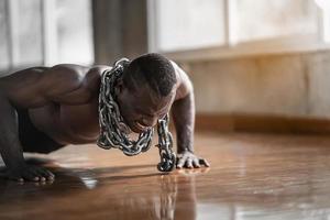 hombre africano usando cadenas haciendo ejercicio push up en el gimnasio. deporte hombre ejercicio en el gimnasio. concepto de deporte