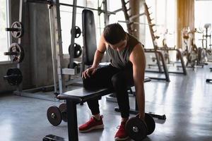 hombre asiático en forma haciendo ejercicio en la sala de pesas en el gimnasio. concepto de hombre deportivo foto