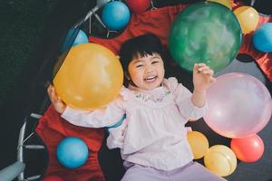 Cute asian girl play on school or kindergarten yard or playground. Little asian girl playing colorful ball at playground. Child playing on outdoor playground. photo