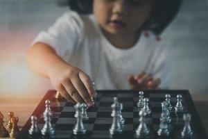 Little asian baby girl playing chess.Smart kid.fashion children. Little genius Child. Intelligent game.Chessboard. Baby activity concept. photo