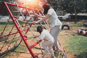young asian mother playing with her baby on the playground. Mom and daughter. Cute baby daughter playing with mom happy funny family concept photo