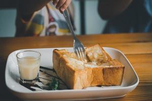 baby eating milk toast with fork on the dining table, cute baby eating toast in the cafe restaurant. Food bakery concept. photo