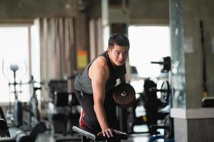 Asian fit sport man working out in weights room at the gym. Sport man concept