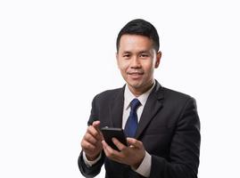 Asian business man wearing suit using mobile phone and smiling on isolated white background. Business concept asian man use mobile to for business on isolated white background. photo