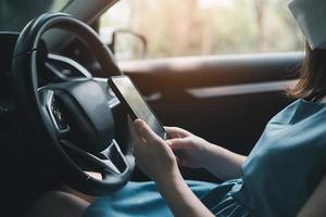 la mujer usa su teléfono móvil para mirar el mapa mientras viaja en automóvil. la mujer está llamando al seguro o a alguien para que la ayude cuando el auto se descompone o tiene un accidente. foto