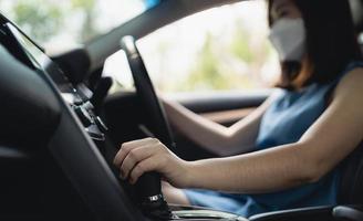 Asian woman wearing surgical mask while driving car. During covid-19 pandemic wearing a mask when you driving car go to outside leaving home. photo