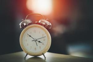 Selective focus of alarm clock on table with bokeh background. Time in life concept. photo