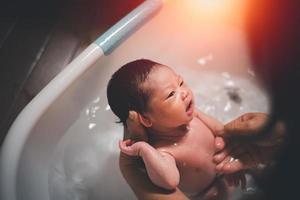 Asian baby girl happy taking a bath by mother at home, asian child baby shower. Baby family concept. photo