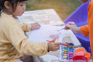 Cute little child painting with colorful paints. Asian girl using paintbrush drawing color.Baby activity lifestyle concept
