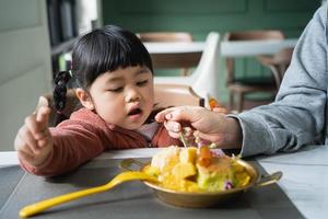 Mother feeding her baby daughter. Happy baby girl eating ice cream with mother in the living room. Family happy food toddler concept photo