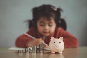 familia ahorrando dinero. la hija de una niña asiática planea pasar el futuro en serio, finanzas y ahorro, familia y concepto financiero. foto