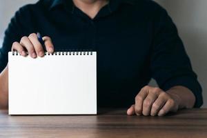 Businessman displays a notebook with a copy area with pen, note taking business and finance goals, business goals and tricks, business success secret ideas, corporate management planning. photo