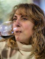 Mature woman tasting a glass of red wine, inside a winery of Oltrepo Pavese, Lombardy, Northern Italy. This area is world famous for its valuable red and sparkling white wines. photo