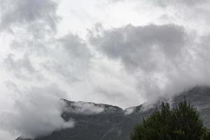 Big Mountain shrouded in incredible clouds and fog in Norway. photo