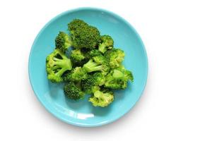 Boiled broccoli in a blue plate isolated on a white background with clipping path. Top view of Vegetables in a dish. Healthy food.