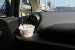 Plastic beverage cups are placed in the cup holder in the car. Cup of iced coffee in car.