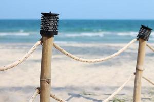 lámparas en postes de cercas de bambú en la playa. foto