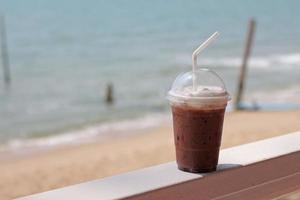 Iced chocolate drink in plastic glasses on a seaside table.