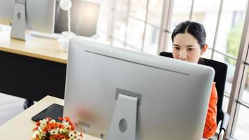 mujer de negocios asiática adulta joven que trabaja con la computadora en el lugar de trabajo de la oficina el día. foto