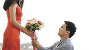 un hombre asiático adulto le da un ramo de flores a su novia en una cita romántica.