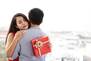 la pareja de hombres le da un regalo romántico en una caja roja a su novia en el día de san valentín. foto