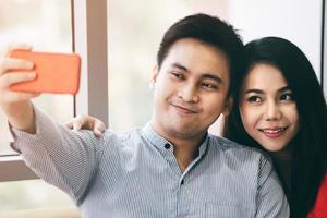 Romantic asian couple take a selfie relax in living room together. photo