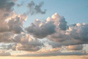 Cumulus clouds in the sky at sunset in summer illuminated by the orange light of the sun. Heavenly magic light. photo