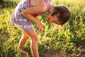 Girl sprays mosquito spray on the skin in nature that bite her hands and feet. Protection from insect bites, repellent safe for children. Outdoor recreation, against allergies. Summer time photo