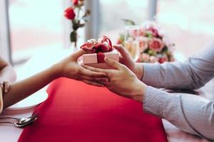 Man couple hand hold a romantic present red gift box give it to girlfriend. photo