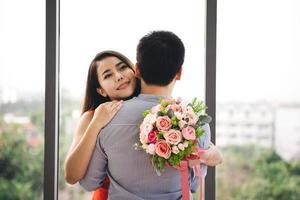 pareja de hombres regala un ramo de flores romántico a su novia. mujer sonríe y abraza juntos. foto