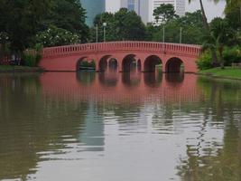 puente de color rojo en el parque. poste de luz. puente de color rojo a través de un lago. parque en tailandia. foto