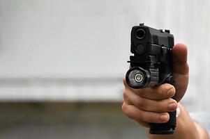 9mm automatic pistol which added troch under the muzzle holding in hand, copy space, soft and selective focus on pistol. photo