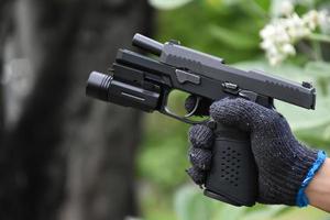 Pistola automática de 9 mm que agregó troch debajo del bozal sosteniendo en la mano, espacio de copia, enfoque suave y selectivo en la pistola. foto