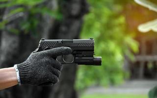 9mm automatic pistol which added troch under the muzzle holding in hand, copy space, soft and selective focus on pistol. photo