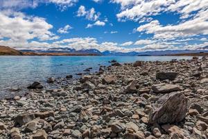 The rock strewn shoreline of Lake Tekapo in the South Island of New Zealand photo