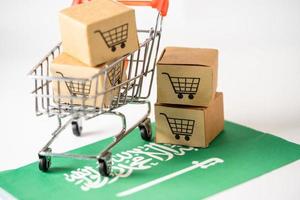 caja con el logotipo del carrito de compras y la bandera de Arabia Saudita, importación, exportación, compras en línea o comercio electrónico, servicio de entrega de finanzas, tienda, envío de productos, comercio, concepto de proveedor. foto