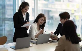 Young beautiful woman gesturing and discussing something with smile while her coworkers listening to her sitting at the office table photo