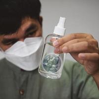 Handsome man put on a mask holding alcohol spray bottle cleaner photo