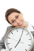 mujer de negocios joven sonriendo sosteniendo un reloj sobre fondo blanco. foto