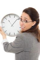 mujer de negocios joven sonriendo sosteniendo un reloj sobre fondo blanco. foto