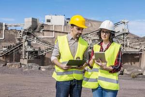 Construction coworkers using tablet on industrial area photo