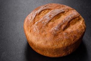 Tasty fresh baked in oven white bread on a dark concrete background photo