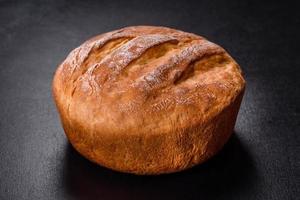 Tasty fresh baked in oven white bread on a dark concrete background photo