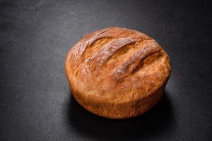 Tasty fresh baked in oven white bread on a dark concrete background photo