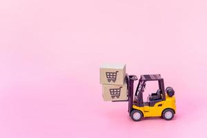 Logistics, and delivery service - Forklift model and paper cartons or parcel with a shopping cart logo on Pink background. Shopping service on The online web and offers home delivery. photo