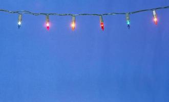 Christmas lights string on blue background with copy space photo